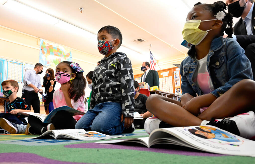 First-graders listen to the interim superintendent of the Los Angeles Unified School District, Megan Reilly, read a book at Normont Elementary School in Harbor City on Aug. 16, the first day of school. Kids listen in a classroom while wearing face masks