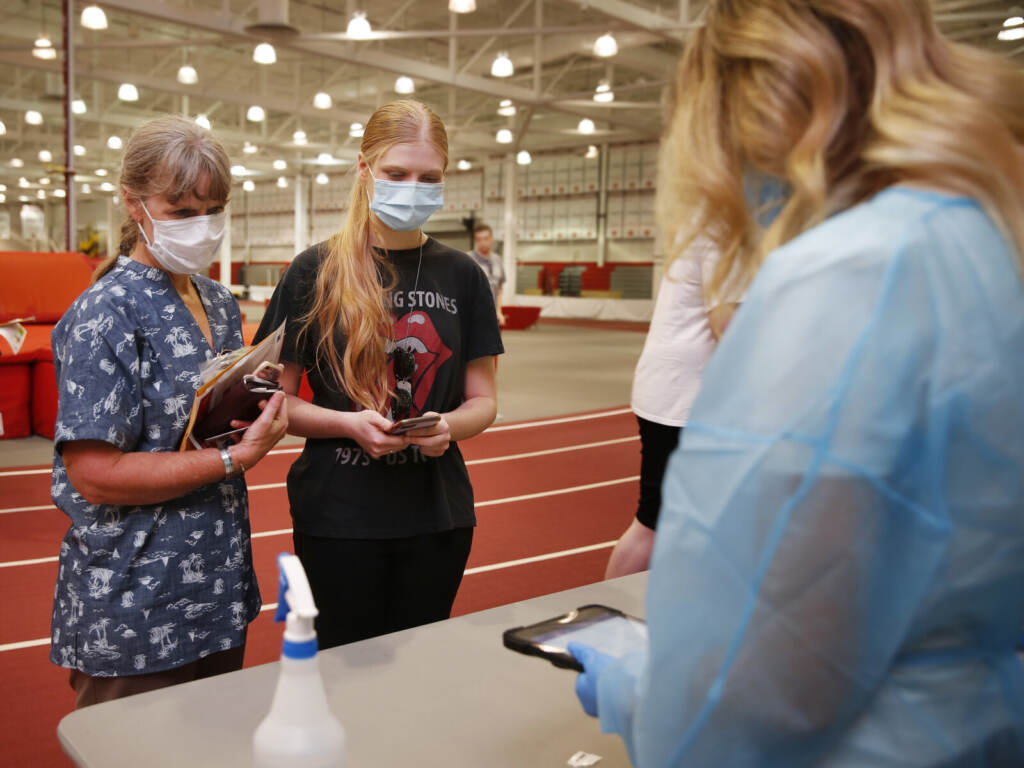 Phoebe Fies and her mom turn in her COVID-19 test inside a school gym