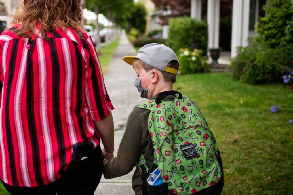 Stephanie Chenard held hands with her son Desmond, 8, as they walked to his school in the San Francisco Bay Area last week. Later that evening the school district reported four positive COVID-19 cases in four different schools. A parent hold their kids hand on their way to school.