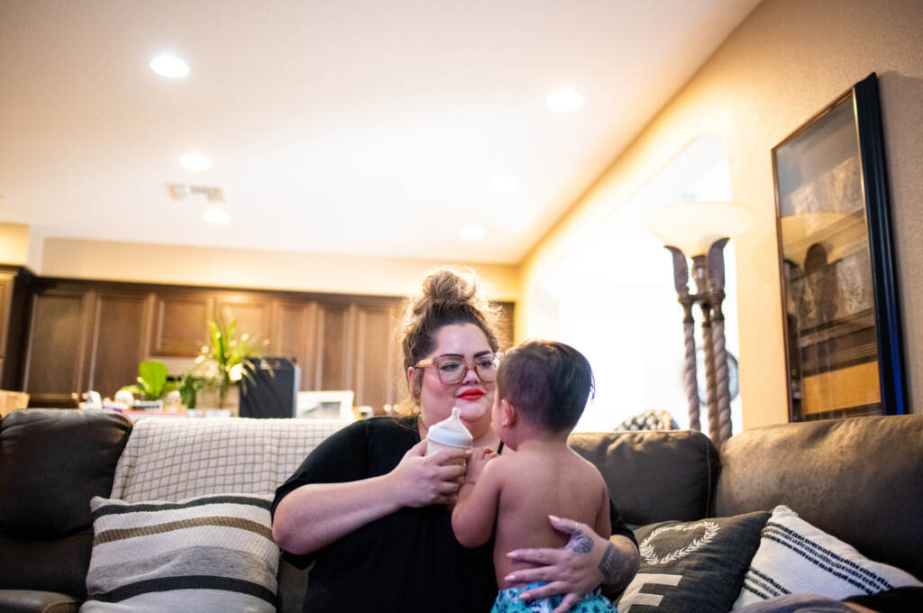A parent holds their child on the couch.