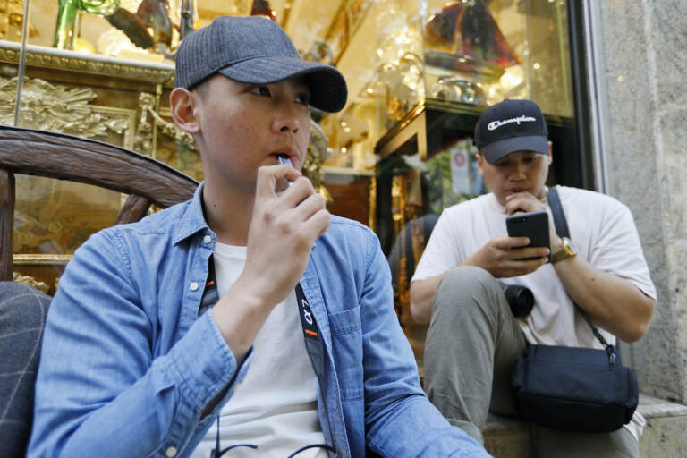 In this Monday, June 17, 2019, file photo, Joshua Ni, 24, and Fritz Ramirez, 23, vape from electronic cigarettes in San Francisco. (AP Photo/Samantha Maldonado, File)