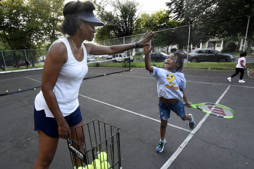 01 Kelly Cass-White gets a high-five from tennis student Harlem Lewis, 6 on Aug. 26, 2021