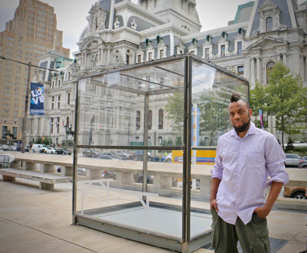 Artist Coby Kennedy stands beside his sculpture on Thomas Paine Plaza, ''Kalief Browder: The Box.''