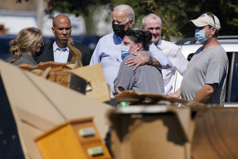 President Joe Biden hugs a person as he tours a neighborhood impacted by Hurricane Ida, Tuesday, Sept. 7, 2021, in Manville, N.J. Sen. Cory Booker, D-N.J., second from left, and New Jersey Gov. Phil Murphy, second from right, look on. (AP Photo/Evan Vucci)