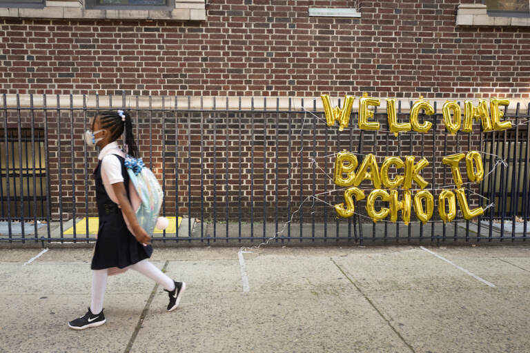 FILE - In this Sept. 13, 2021, file photo, a girl passes a 'Welcome Back to School' sign as she arrives for the first day of class. (AP Photo/Mark Lennihan, File)