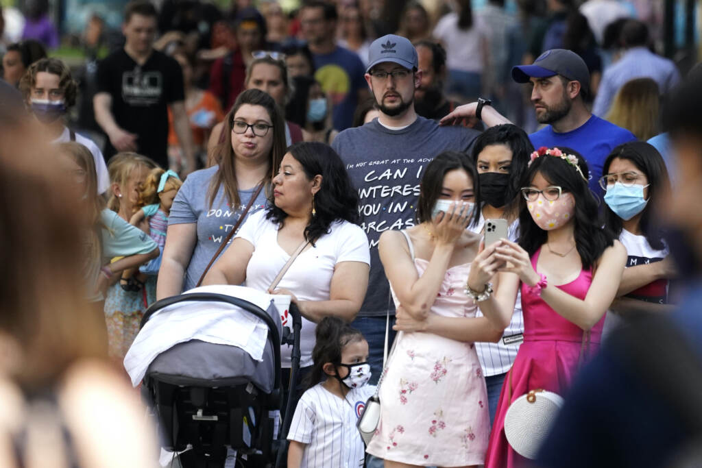 Virus Outbreak Illinois People wait to cross the street, some wearing face masks