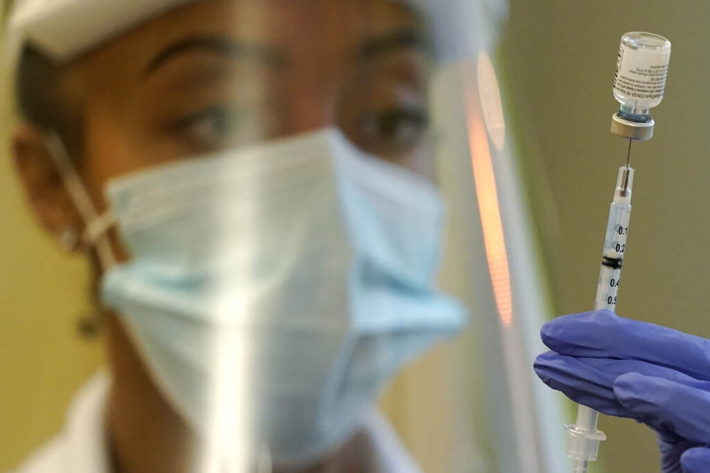 Virus Outbreak Boosters A pharmacist prepares a syringe of the Pfizer vaccine for COVID-19