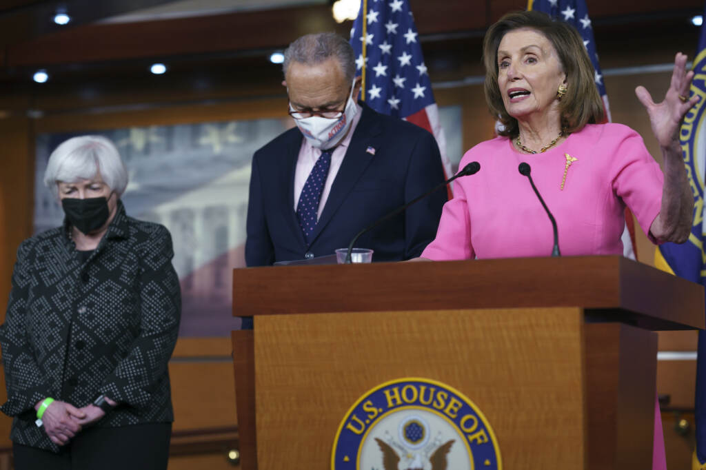 Nancy Pelosi stands at a podium, with Chuck Schumer and Janet Yellen standing to her right