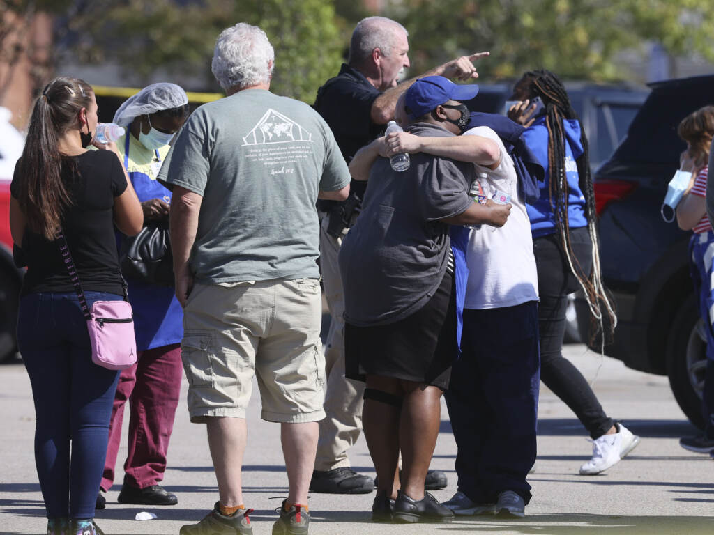 People embrace as police respond to the scene of a shooting at a Kroger grocery store in Collierville, Tenn., on Thursday. Police say 13 people were injured, one of whom has died. The suspected shooter also died from what police say was a self-inflicted gunshot wound. People embrace as police respond to the scene of a shooting at a Kroger's grocery store in Collierville, Tenn., on Thursday, Sept. 23, 2021