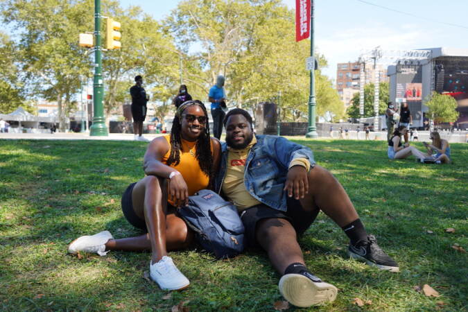 Mikaila Douglass, 22, and Boris Fabre, 23, sit under the shade as they wait for the first act to perform