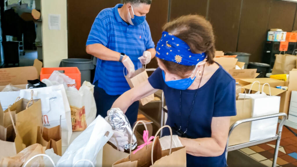 YOK-10-1 Two people packing brown bag meals at a shelter