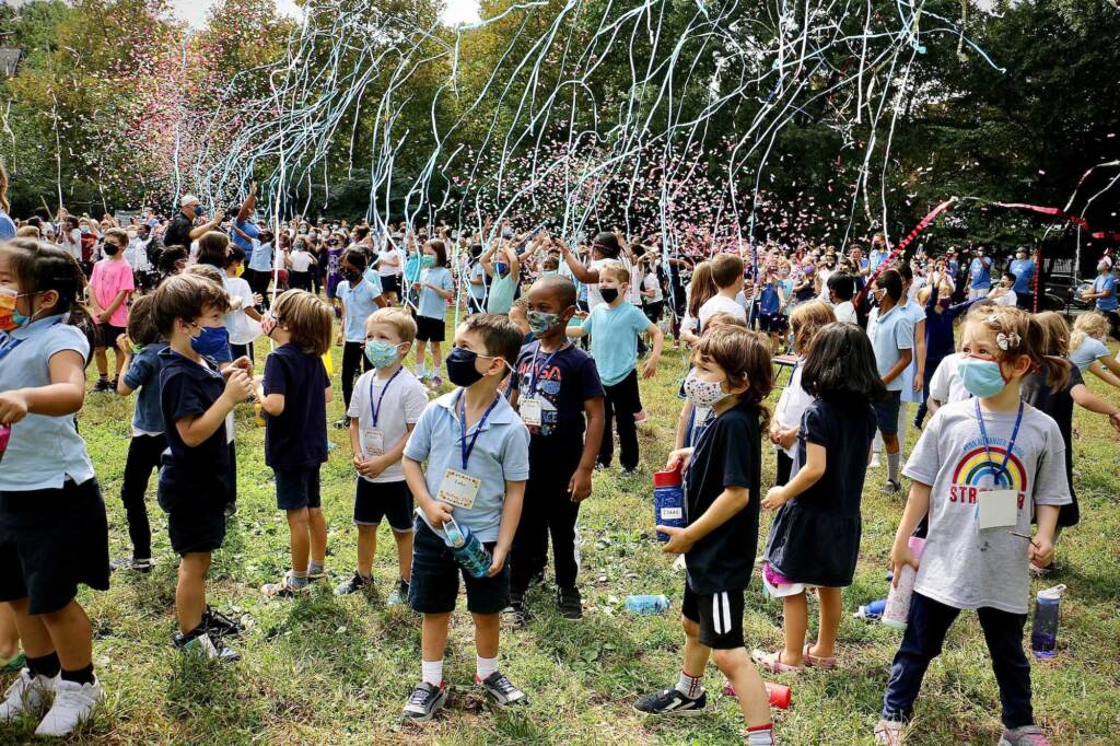 blue_ribbon_school_ceremony_EL_01_092121 Kids, wearing masks, are surrounded by confetti outside during a ceremony