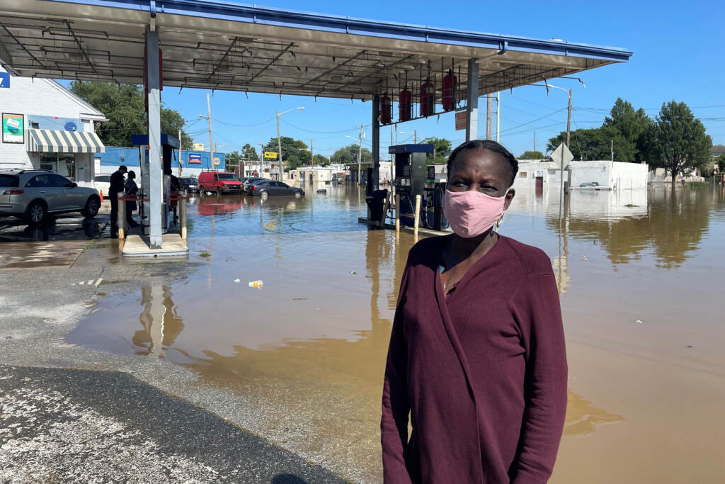 dolley-cbrs Andrienne Dolley stands in front of a gas station surrounded by floodwaters