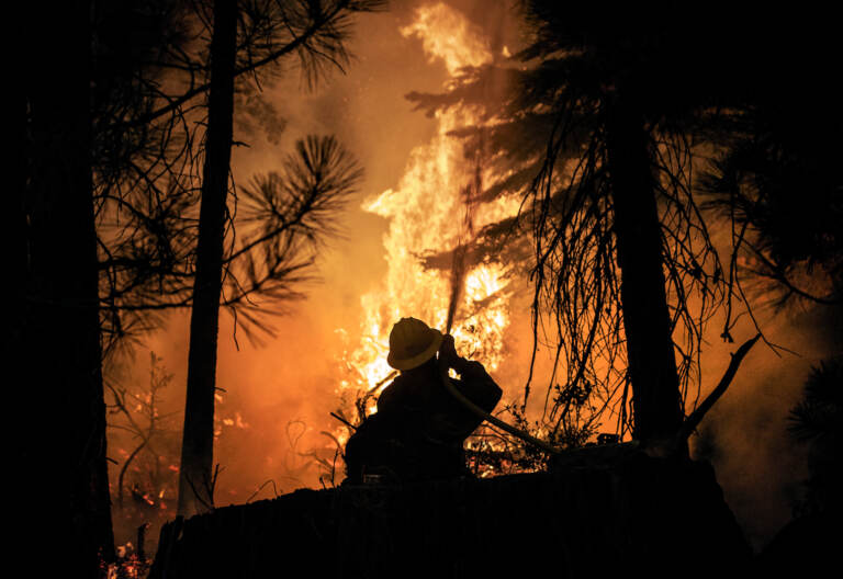A firefighter with the U.S. Forest Service protects the Strawberry General Store on Highway 50 in El Dorado County after a backfire was set, Saturday, Aug. 28, 2021, against the advancing Caldor Fire