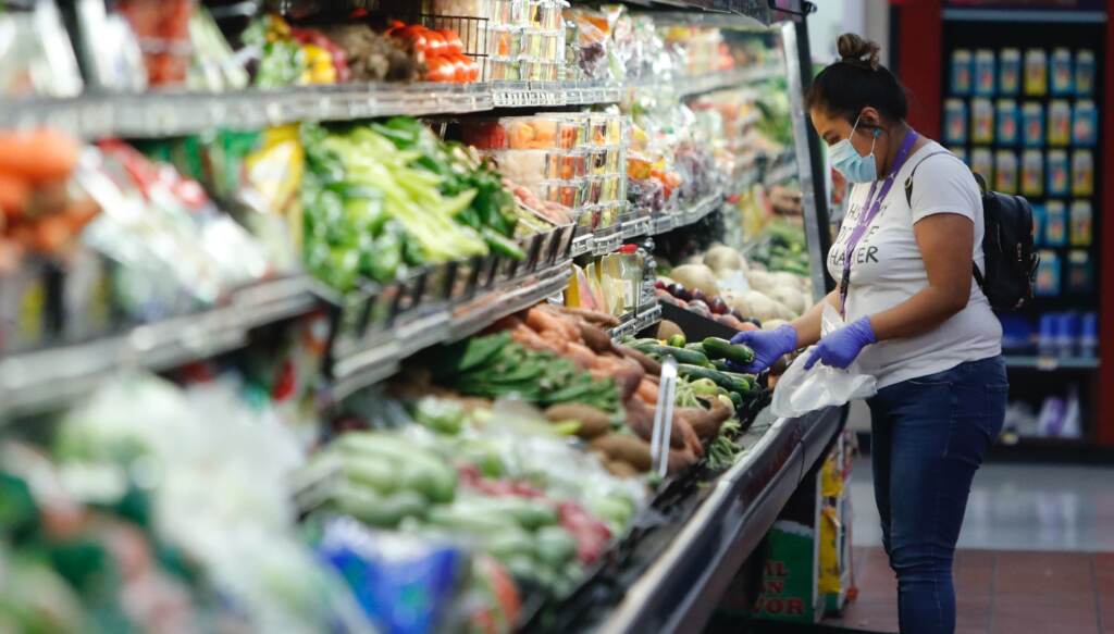 grocery A woman wears a mask while shopping the produce section
