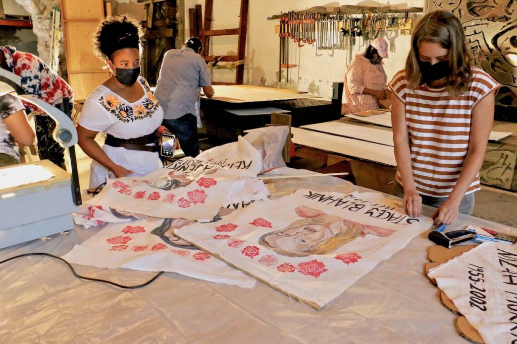 Spiral Q co-directors Jennifer Turnbull (left) and Liza Goodell work on memorial banners to be carried in the Philly Trans Parade. The banners survived the flood at Spiral Q's storage facility in Mont Clare, Pa