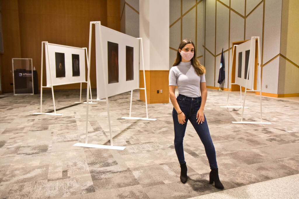 2021 10 06 k paynter seeking Katherine Cambareri, a graduate with a masters degree in public health from Jefferson College of Population Health, stands with her photographs of clothes worn by survivors of sexual violence at her exhibit at Eakins Lounge at Jefferson Alumni Hall on October 6, 2021. (Kimberly Paynter/WHYY)