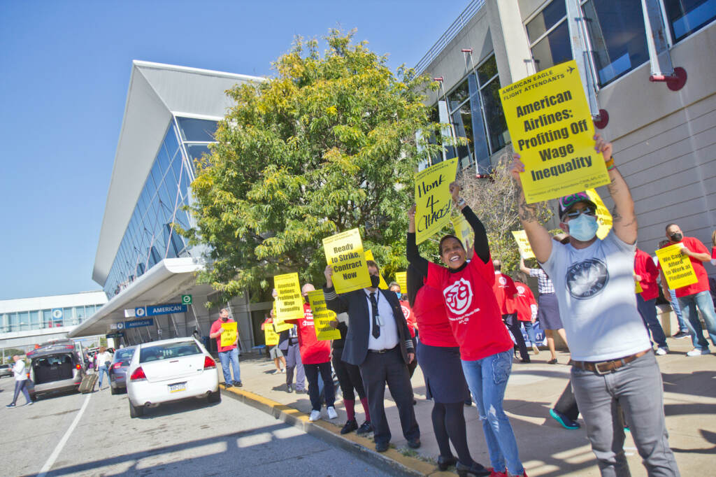 Workers hold up yellow signs at a protest outside PHL Airport