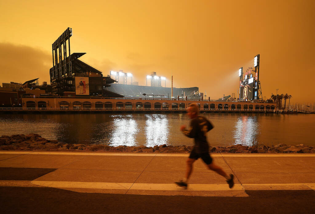 Climate Health Problems A jogger runs along McCovey Cove outside Oracle Park, under darkened skies from wildfire smoke