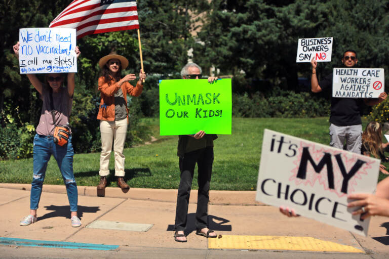 Protesters hold signs denouncing vaccine and mask mandates
