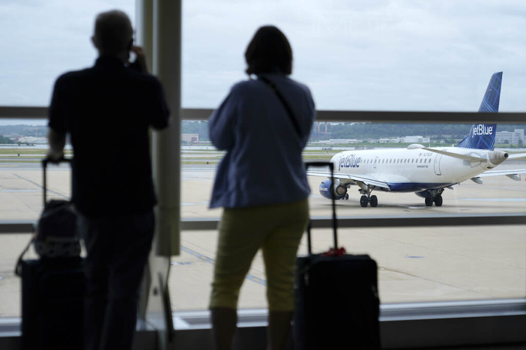 Virus Outbreak Airlines Travelers watch a JetBlue Airways aircraft taxi away from a gate at Ronald Reagan Washington National Airport†ahead of Memorial Day weekend, Tuesday, May 25, 2021, in Arlington, Va