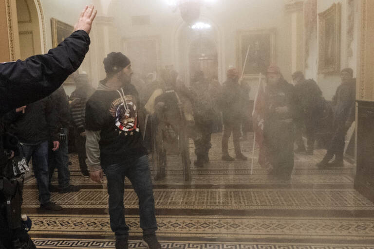 In this Jan. 6, 2021, file photo, smoke fills the walkway outside the Senate Chamber as supporters of President Donald Trump, including Eric Bochene, far right, are confronted by U.S. Capitol Police officers inside the Capitol in Washington. (AP Photo/Manuel Balce Ceneta, File)