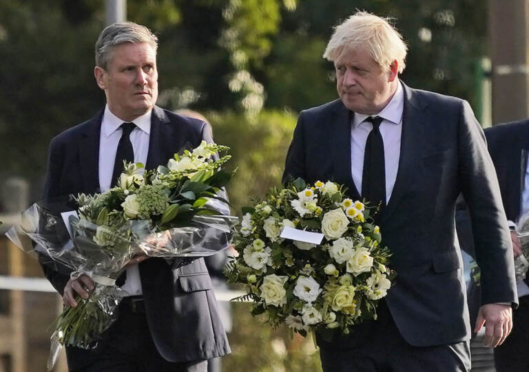 British Prime Minister Boris Johnson, right, and Leader of the Labour Party Keir Starmer carry flowers as they arrive at the scene where a member of Parliament was stabbed Friday, in Leigh-on-Sea, Essex, England, Saturday, Oct. 16, 2021