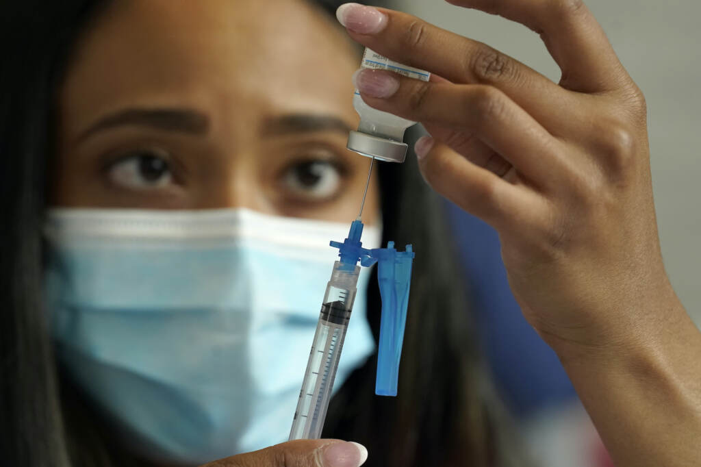 A nurse draws a Moderna COVID-19 vaccine into a syringe