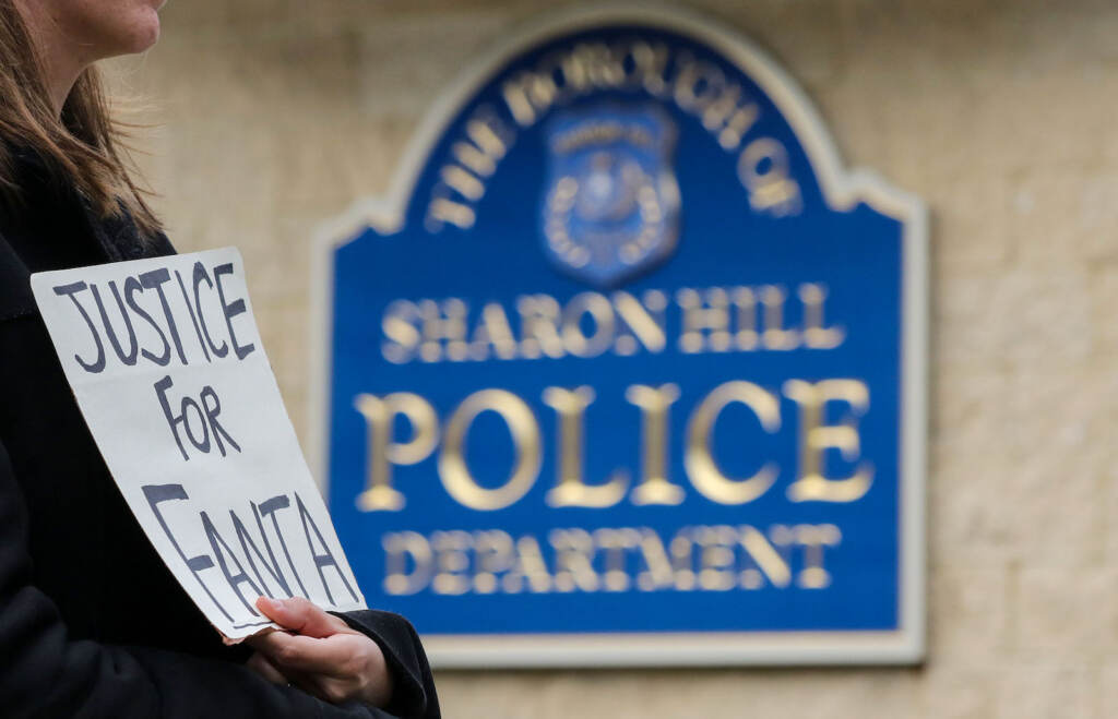 Heminghaus-Silent March for Fanta_016 A person holds a sign that reads Justice for Fanta in front of a sign that reads Sharon Hill Police Department.