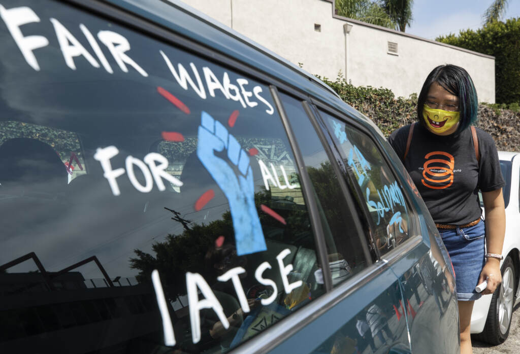 Crystal Kan, a storyboard artist, draws signs on cars of IATSE union members during a rally in Los Angeles in September. (Myung J. Chun/Getty Images)