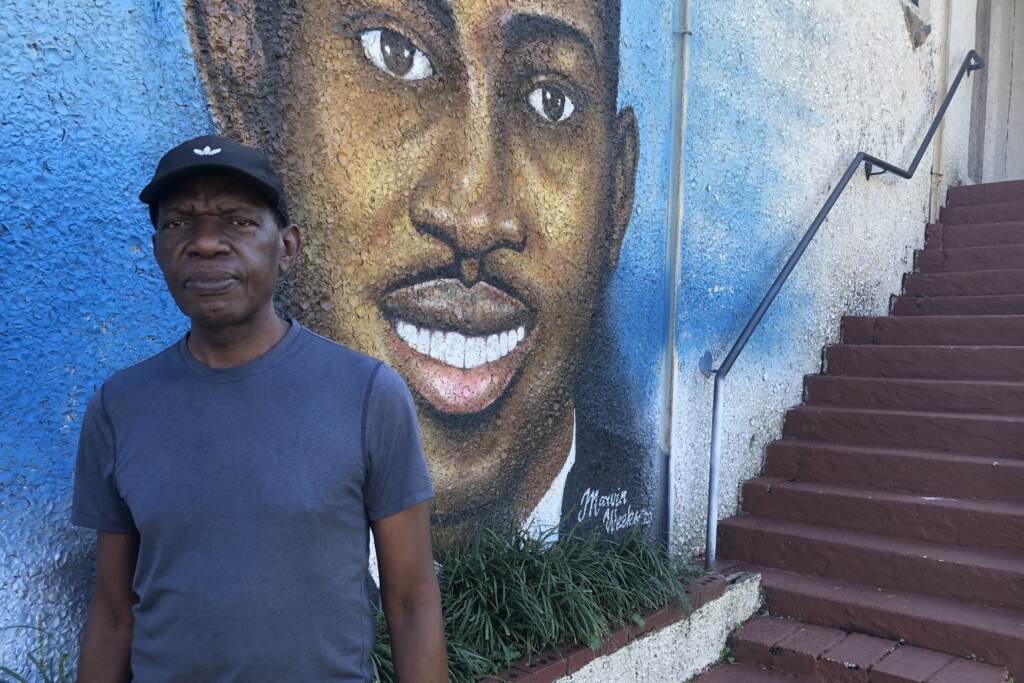Marvin Weeks in front of his mural of Ahmaud Arbrery.