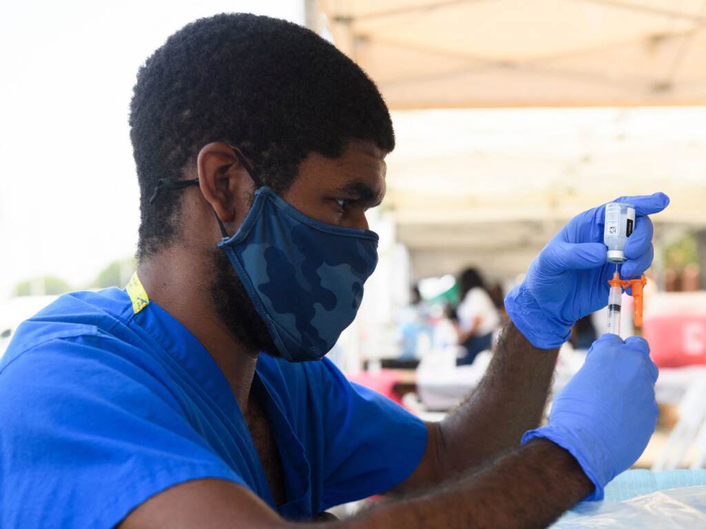 A health care worker prepares a dose of the Moderna COVID-19 vaccine during a clinic held at the Watts Juneteenth Street Fair in the Watts neighborhood of Los Angeles. A health care worker prepares a dose of the Moderna COVID-19 vaccine during a clinic held at the Watts Juneteenth Street Fair in the Watts neighborhood of Los Angeles. (Patrick T. Fallon/AFP via Getty Images)