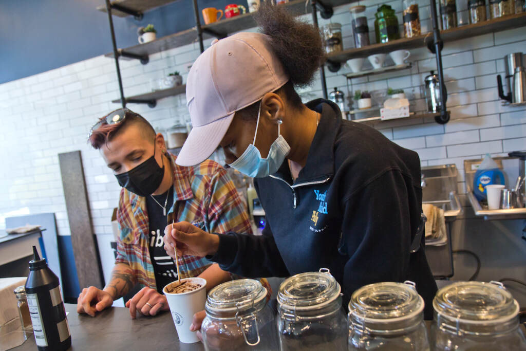 2021 11 10 k paynter stomping grounds cafe-6 Kim Paulus, general manager of Stomping Grounds Cafe in West Philadelphia and Workforce Development Instructor at Youthbuild Charter High School (left), teaches senior Nyasia Flowers (right) to create a design on a mocha drink