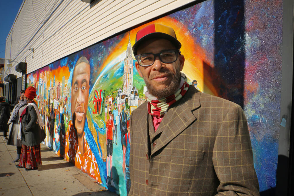Randall Whitfield stands in front of a George Floyd mural