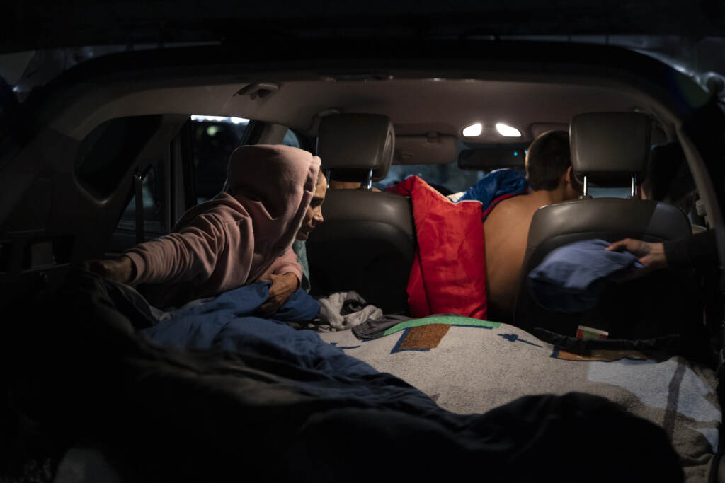 Veronica Vargas helps her children get ready for bed. The boys sleep in the back of the car while Veronica and Alex work the overnight shift.