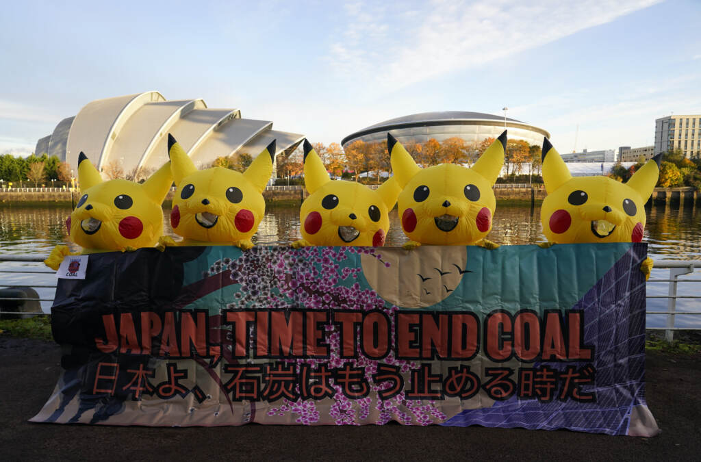 Climate COP26 Summit Activists dressed as the Pokemon character Pikachu hold a sign that says,