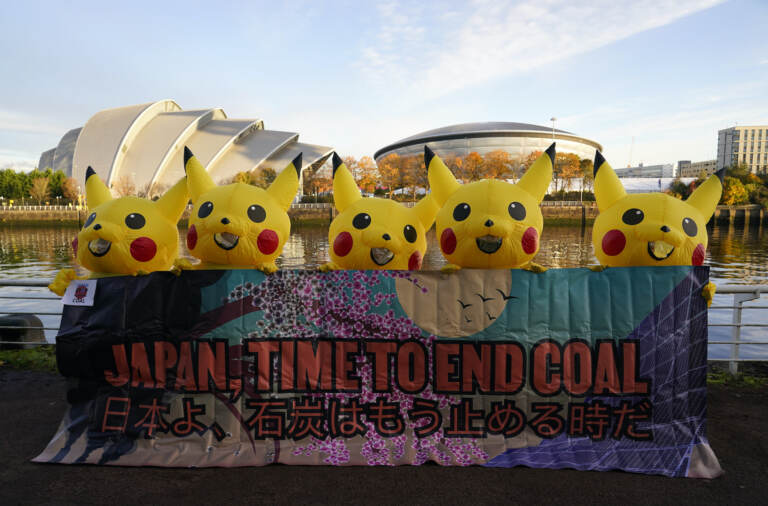 Activists dressed as the Pokemon character Pikachu hold a sign that says, 