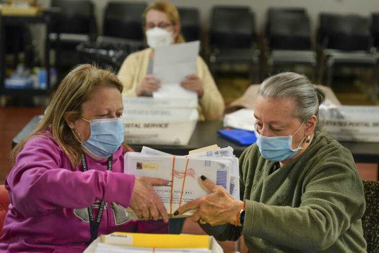 Bernadette Witt, left, and JoAnn Bartlett, right, process and double-check mail ballots