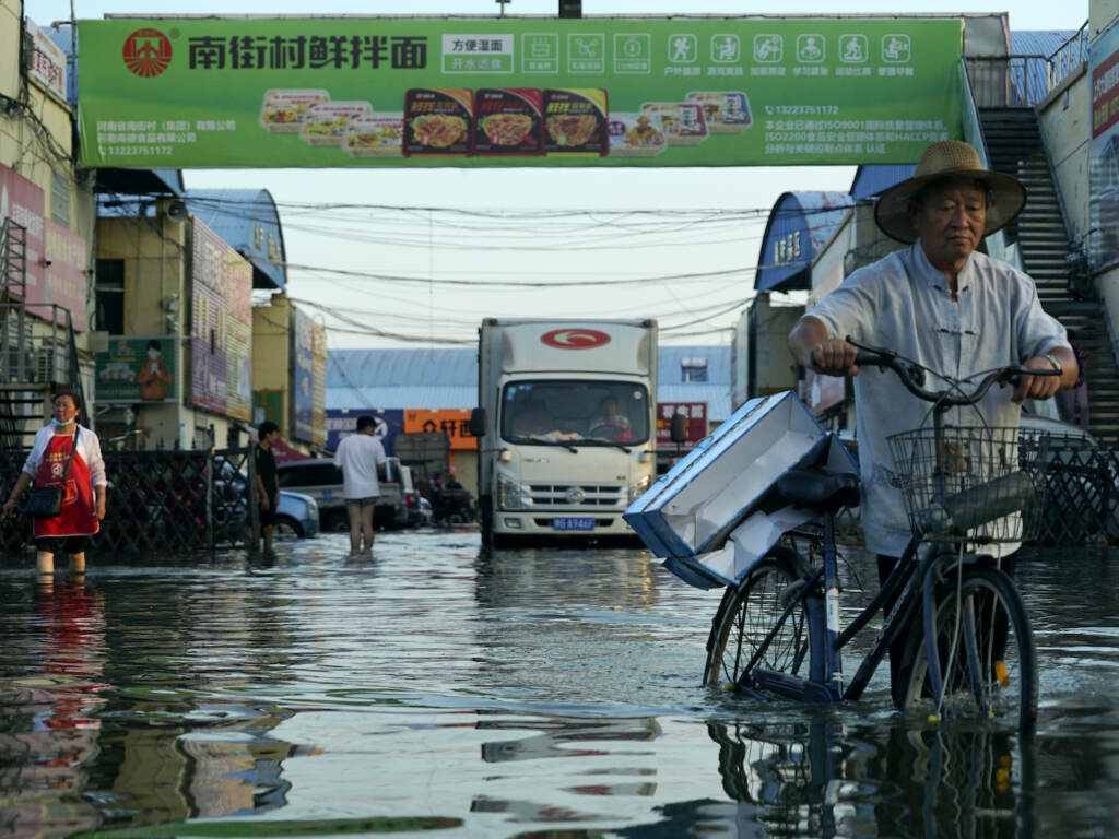 UN Climate Report A man carries goods on his bicycle through floodwaters in China