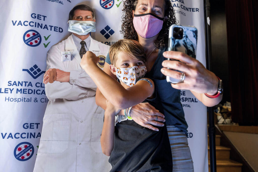 APTOPIX Virus Outbreak Kids Vaccine Finn Washburn shows his vaccination site as mom Kate Elsley takes a photo