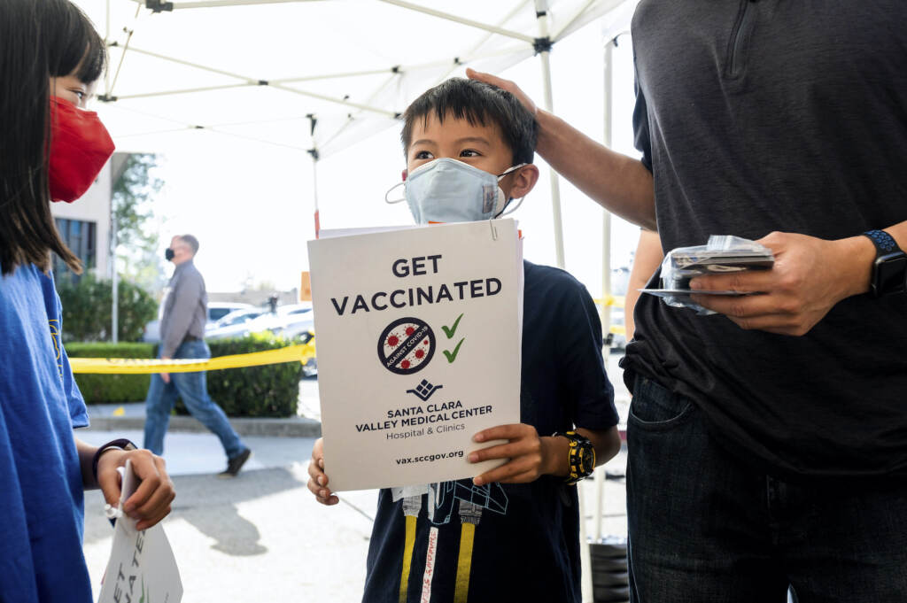 Virus Outbreak Kids Vaccine Matthew Yip holds up a paper that says,