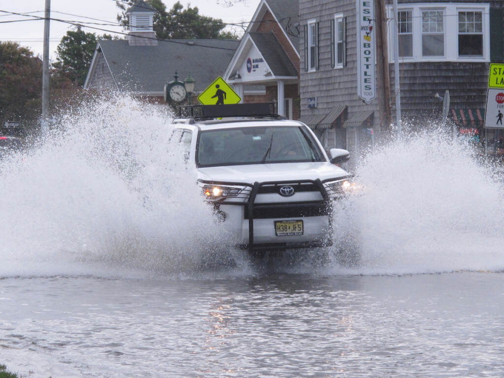 Jersey Shore Flooding This Oct. 11, 2019 photo shows a car kicking up spray while driving through a flooded street in Bay Head, N.J. Bay Head is moving forward with its own proposed solutions to back bay flooding in response to