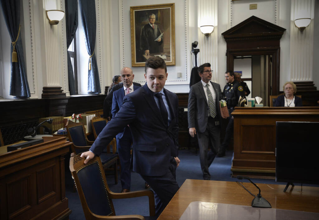 Kenosha Protest Shootings Kyle Rittenhouse, center, pulls out his chair for a meeting Judge Bruce Schroeder called during his trial at the Kenosha County Courthouse in Kenosha, Wis., on Thursday, Nov. 18, 2021