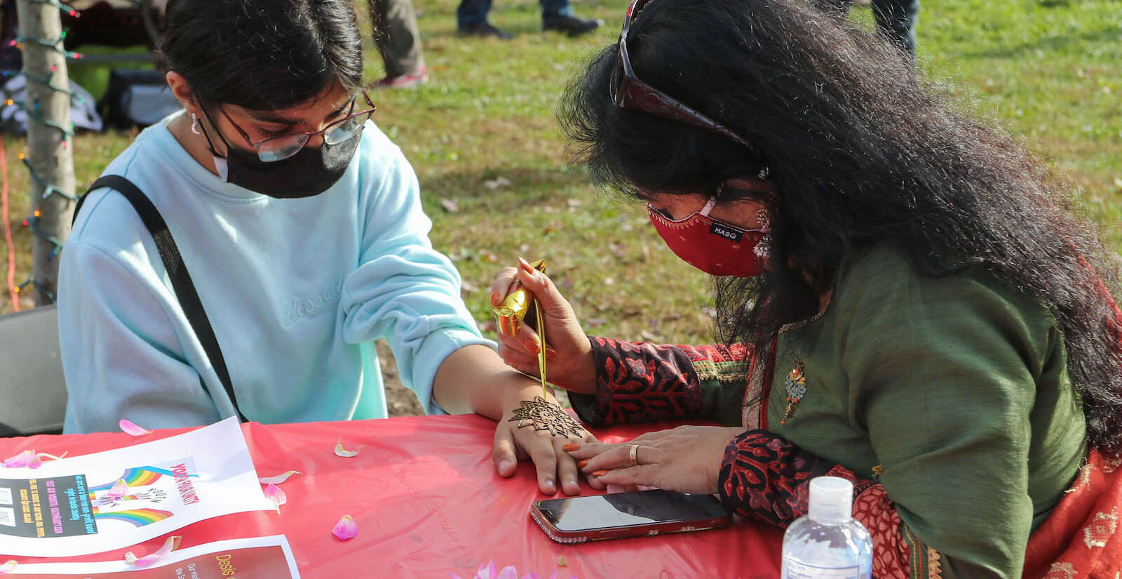 Suri Yeghen, of Buckingham, getting a henna tattoo from Bina Bengali, of Fountainville at the first annual Diwali festival in Doylestown on Nov. 7, 2021. (Daniella Heminghaus for WHYY)