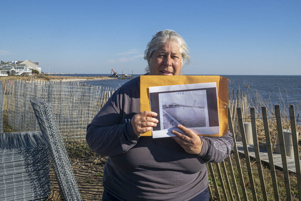 Pat Doyle holds up a black-and-white photograph of a large pool that was once a centerpiece of the Bayside Beach Club