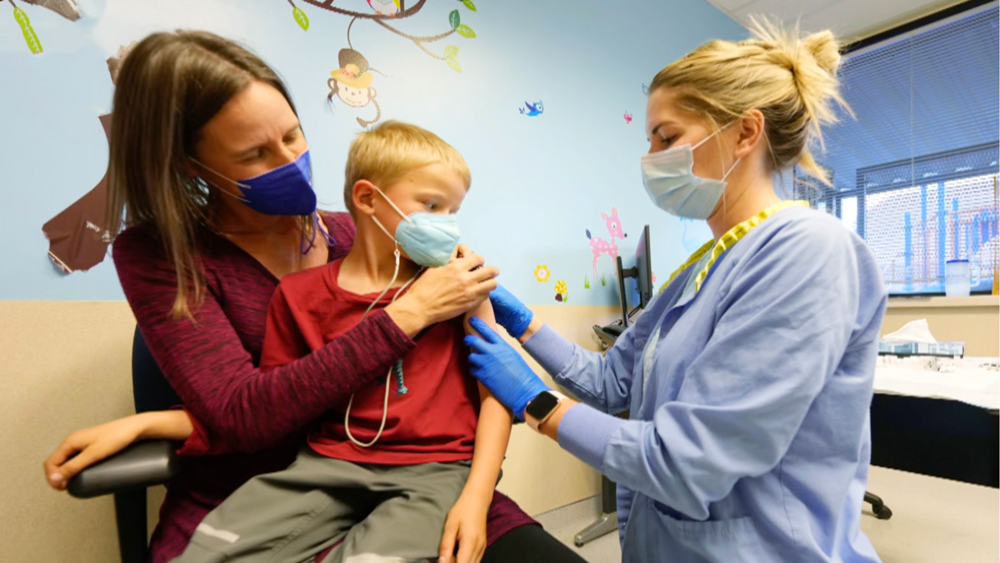 A child with his mother getting the COVID-19 vaccine in a doctor's office