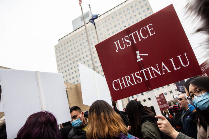 A protester wearing a face mask holds a sign that says, 