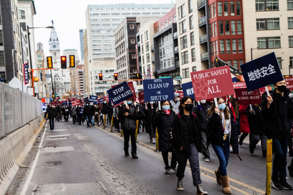 anti-bullying-violence-rally-septa-AAPI-KP-113021-07 Protesters march down a Philadelphia street with signs that say,