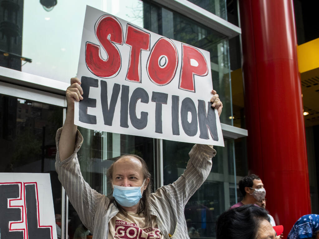 Housing advocates pushing for stronger evictions protections in New York in August, the same month the U.S. Supreme Court struck down a federal eviction moratorium from the CDC. In the wake of that decision, evictions are now rising in parts of the country that don’t have any local protections. A housing advocate holds up a sign that says,