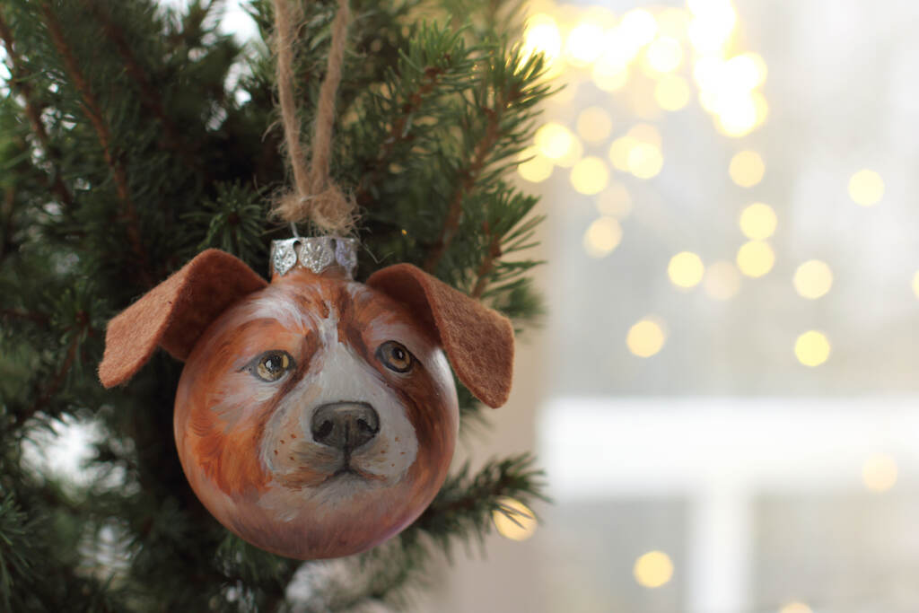 Glass Ball In The Image Of A Dog Decorates A Christmas Tree For A Holiday / Celebration Of The New Y A Christmas glass ball decoration depicting a dog's face